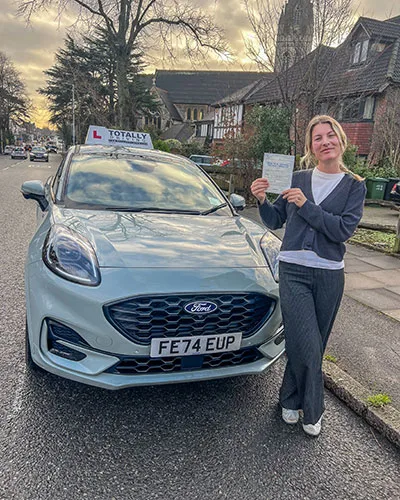 Totally driving student with pass certificate standing in front of car