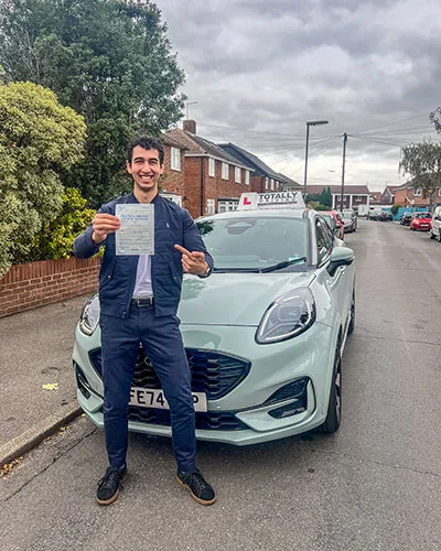 Totally driving student with pass certificate standing in front of car
