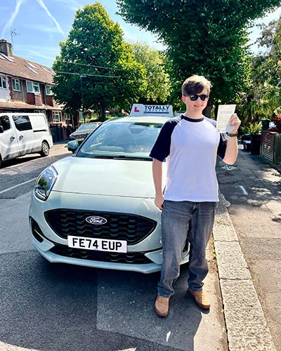 Totally driving student with pass certificate standing in front of car