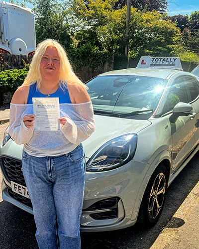 Totally driving student with pass certificate standing in front of car