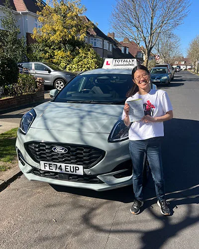 Totally driving student with pass certificate standing in front of car