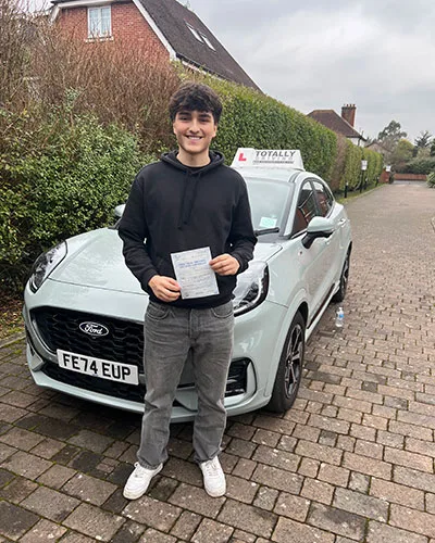 Totally driving student with pass certificate standing in front of car